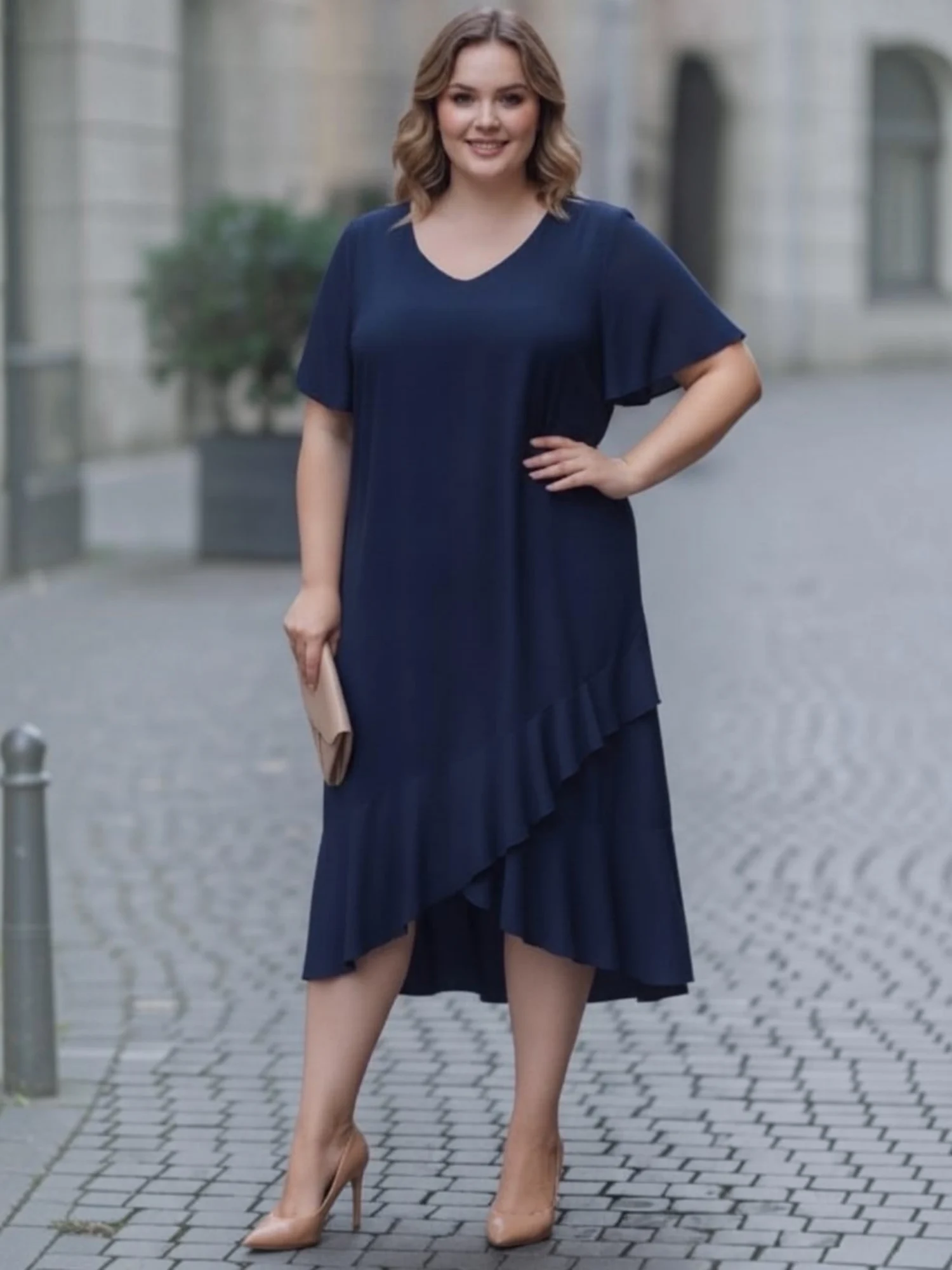 Sukienka Fari: przód sukienki z dekoltem V i falbaną, ujęcie z boku, z ręką na biodrze.