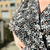 Lili sukienka asymetryczna: beżowa sukienka w czarne kropki, ujęcie przodu, eksponujące wiązanie w talii.