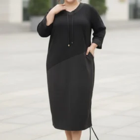 Sukienka damska Adelina, ujęcie z przodu z dłonią w kieszeni, podkreślające praktyczne detale.
