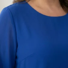 Spodnie damskie Komplet damski wizytowy: zbliżenie na gładki materiał bluzki i detale dekoltu.