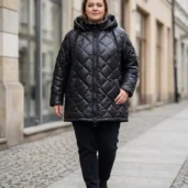 Pikowana kurtka z kapturem, widok z przodu, ukazujący model w ruchu i kontrastowy zamek.