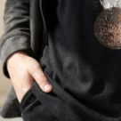 Czarna bluzka z dekoltem V i artystycznym wzorem kół – zbliżenie na dolną część bluzki i fragment wzoru.