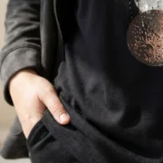 Czarna bluzka z dekoltem V i artystycznym wzorem kół – zbliżenie na dolną część bluzki i fragment wzoru.