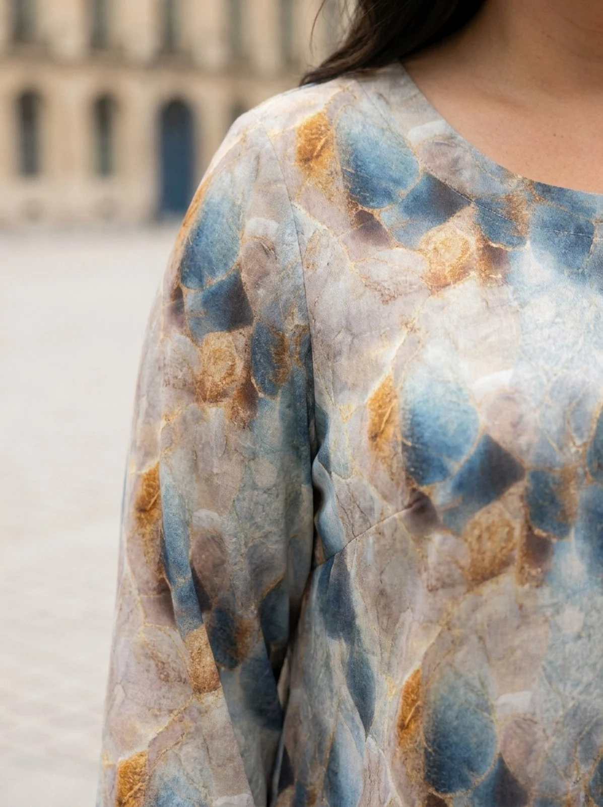 elegancka-bluzka-plus-size-w-niebiesko-zloty-wzor Bluzka damska Elegancka bluzka plus size w niebiesko-złoty wzór, zbliżenie na dekolt i wzór materiału.
