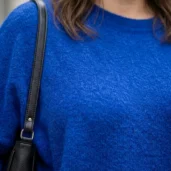 Chabrowy sweter damski z miękkiej dzianiny, zbliżenie na dekolt i fakturę materiału.