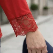 Bluzka w dużych rozmiarach czerwona z koronką, zbliżenie na elegancki koronkowy mankiet rękawa.