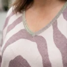 Tunika damska sweterkowa plus size, zbliżenie na dekolt V z ozdobną, błyszczącą lamówką.