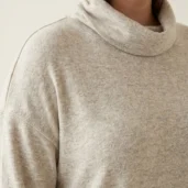 Sweter damski Ciepły beżowy sweter plus size, zbliżenie na miękki golf i obniżoną linię ramion.