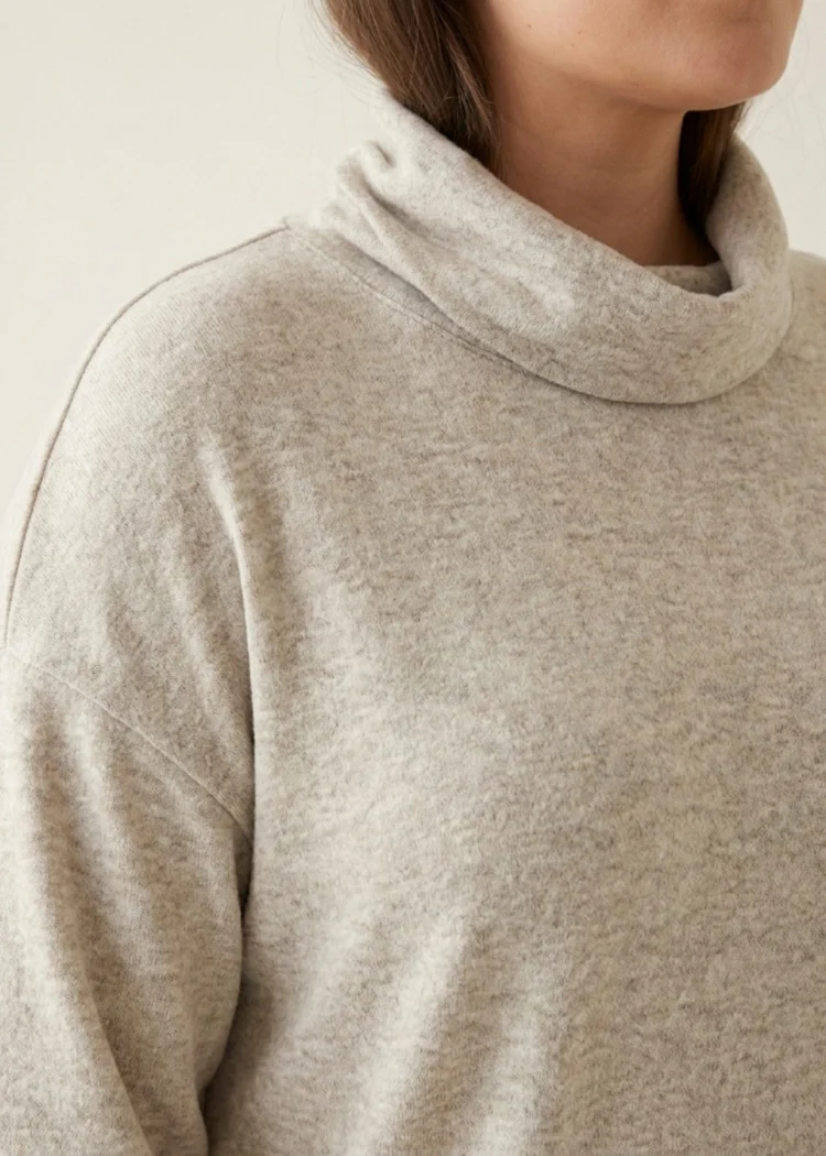 Sweter damski Ciepły beżowy sweter plus size, zbliżenie na miękki golf i obniżoną linię ramion.